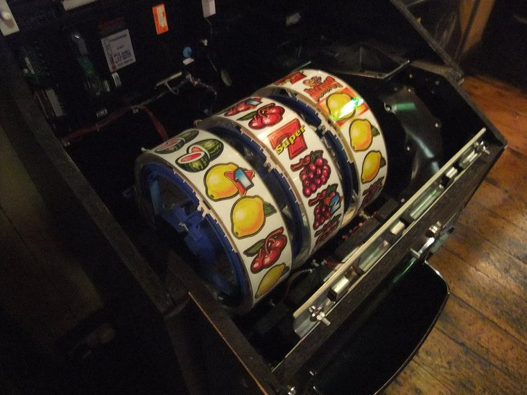 Opengeklapte fruitautomaat: de drie rollen met kersen, citroenen en zevens van binnenuit gezien.