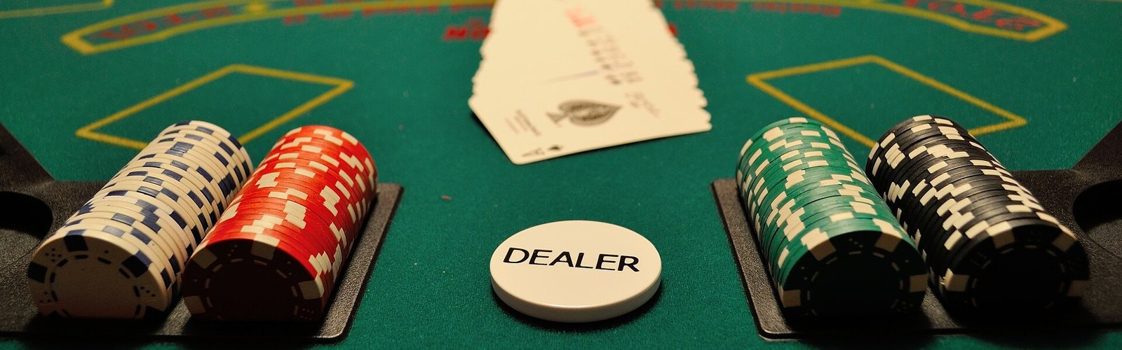 Stapels fiches naast de dealerknop op een speeltafel.