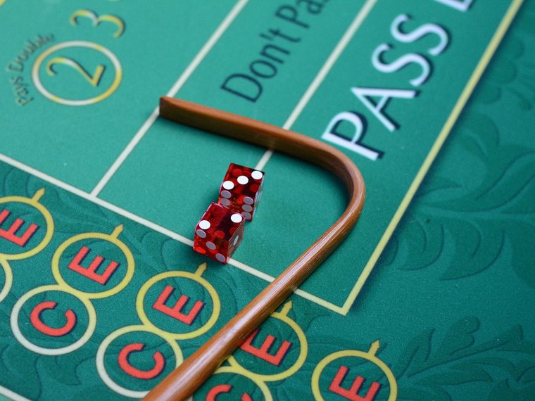 Het harkje van de croupier en twee dobbelstenen op het laken van een craps-tafel.